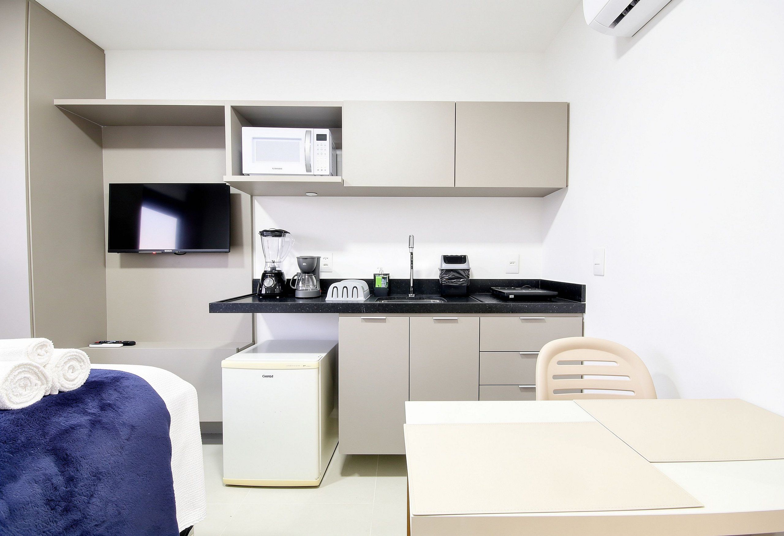 A compact kitchenette with a microwave, toaster, coffee maker, and a small refrigerator.