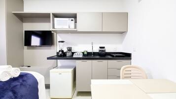 A compact kitchenette with a microwave, toaster, coffee maker, and a small refrigerator.