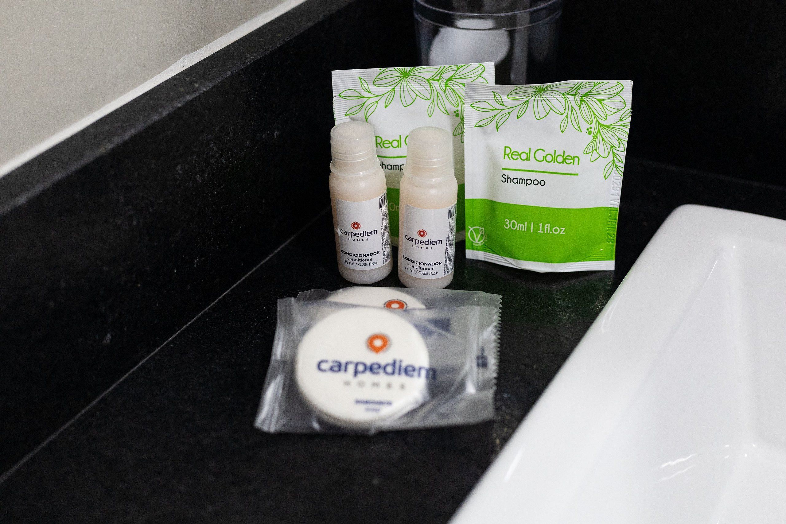 A bathroom counter with a bottle of conditioner, a bottle of shampoo, and a bar of soap.