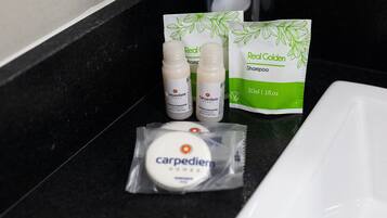 A bathroom counter with a bottle of conditioner, a bottle of shampoo, and a bar of soap.