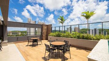 Una terraza en la azotea con una mesa redonda y sillas, una piscina y vistas a la ciudad.