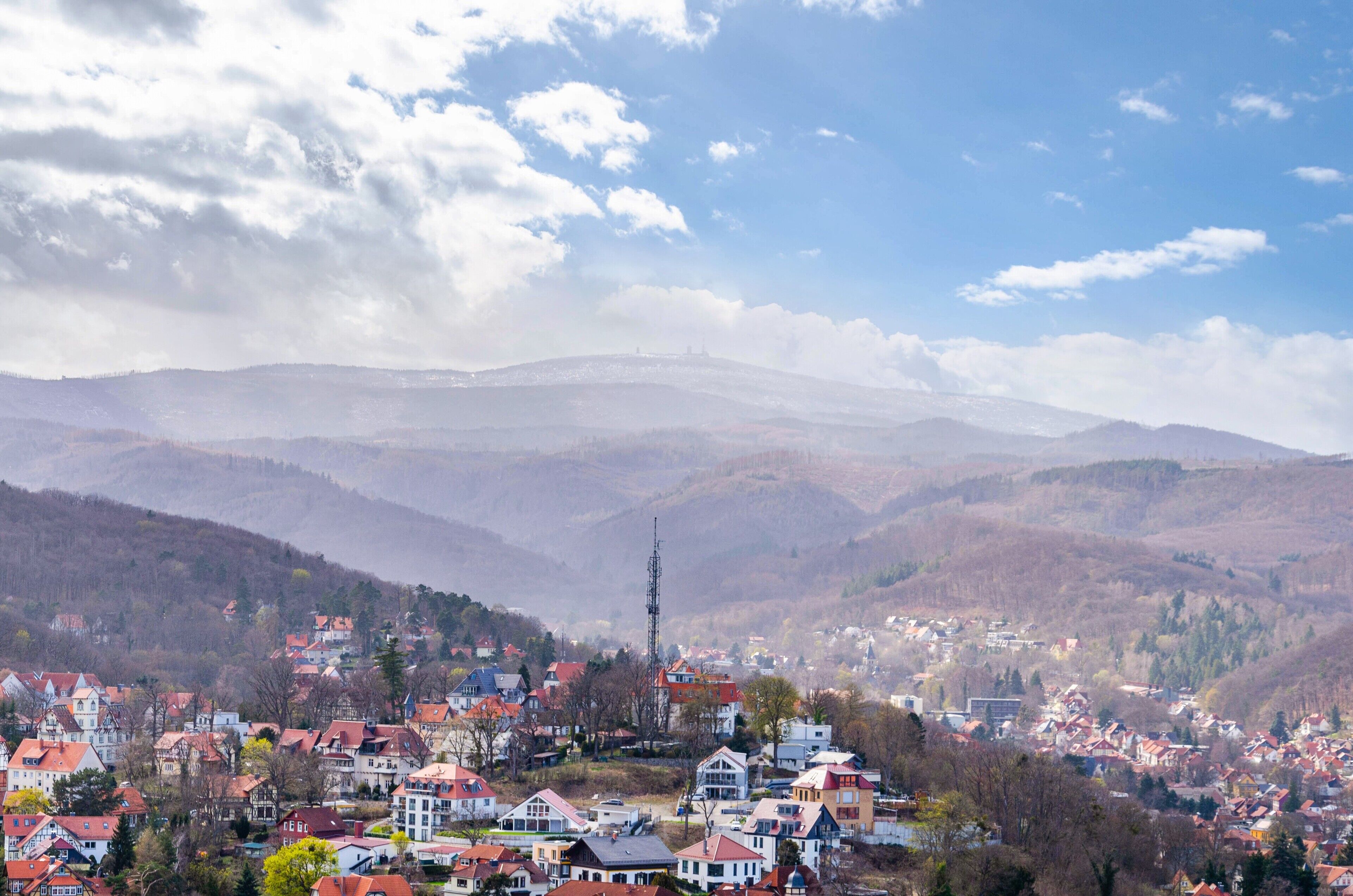 A town nestled in a valley with a prominent church spire, surrounded by hills and a clear sky.