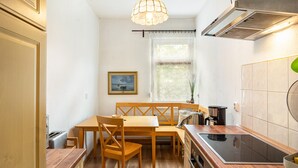 Une cuisine compacte comprenant une table à manger, des chaises, une cuisinière et un luminaire suspendu.