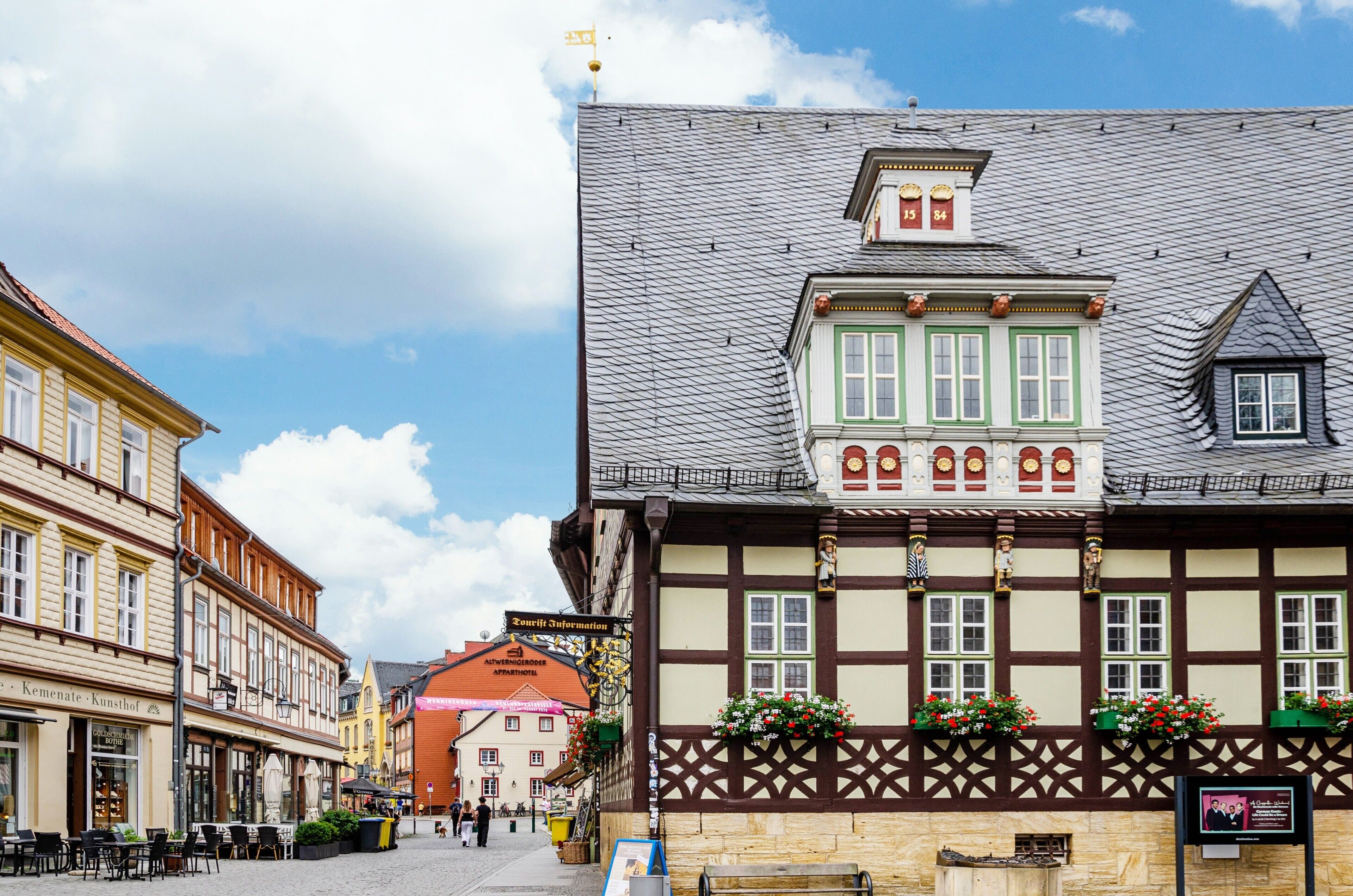 A traditional half-timbered building with a sign for 'Tourist Information' and a red-roofed building in the background.