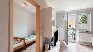 A compact room with a bed, a TV, and a radiator. - Apartment for 6 Guests (57 m²) with Private Terrace and Wi-Fi (Kalkhorst)