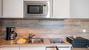 A kitchen with a built-in microwave, a coffee maker, a sink, and a countertop with drawers. - Apartment for 6 Guests (57 m²) with Private Terrace and Wi-Fi (Kalkhorst)