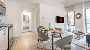 Una cocina moderna con comedor, un televisor en la pared y vistas al exterior.