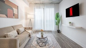 A modern living room with a sofa, coffee table, and a large plant. - Modern 1BR in Old Montreal + Lounge Access (Montreal)