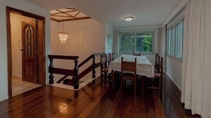 Un'area pranzo con una scala in legno, un lampadario e vista attraverso una finestra.