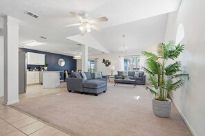 Ein geräumiges Wohnzimmer mit grauem Sofa, einem Couchtisch und einer großen Kübelpflanze.