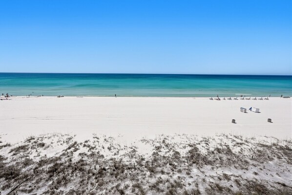 Ein Strand mit blauem Himmel, sandigem Ufer und einigen Personen.