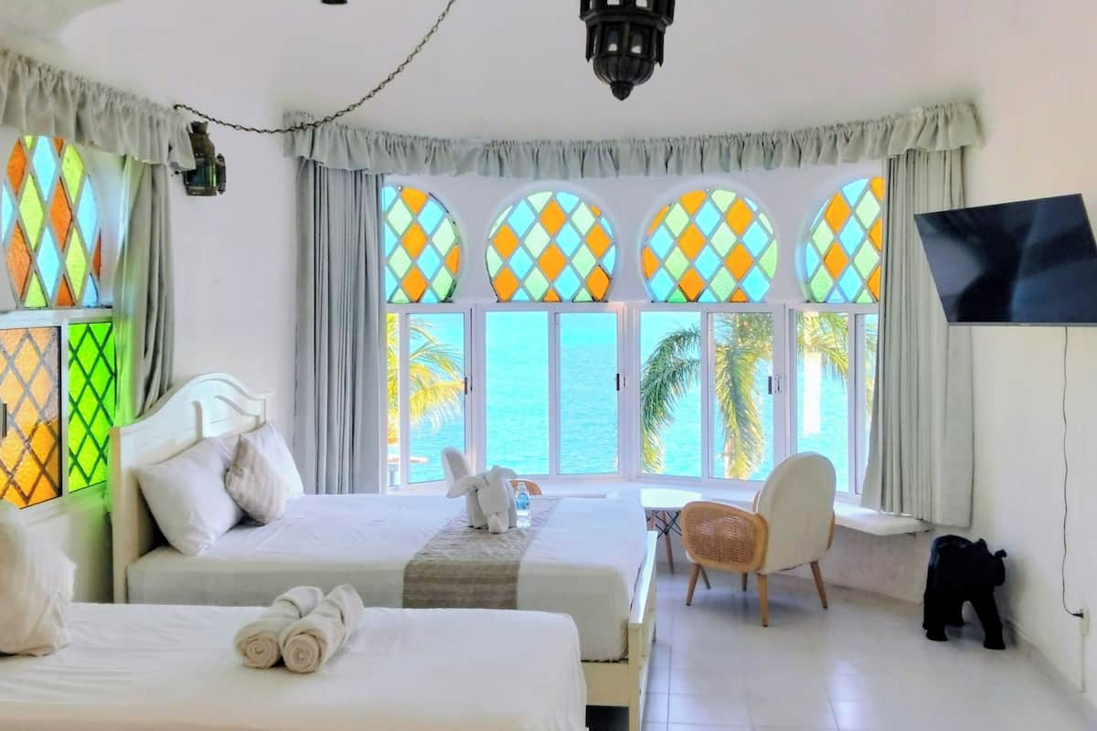 Habitación de hotel con dos camas, televisor, una mesita y una silla.