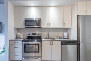 A modern kitchen with stainless steel appliances, including a microwave, oven, and refrigerator. - Central -Parking- 100 walkscore (Montreal)