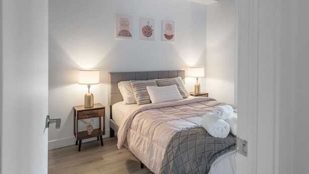 A neatly arranged bedroom with a bed, two bedside tables, and wall art. - Central -Parking- 100 walkscore (Montreal)