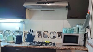 Een kleine keuken met een gasfornuis, magnetron en oven.