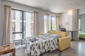 Ein modernes Schlafzimmer mit Bett, Schreibtisch und Blick ins Freie.