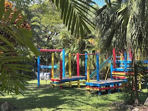 Ein Spielplatz mit bunten Spielgeräten und einem Schild, das zu Beaufsichtigung auffordert.