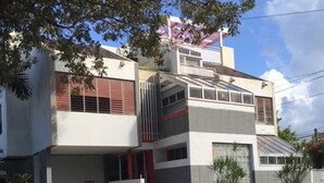Un edificio a due piani con tetto piatto, un garage visibile e un'auto parcheggiata davanti.