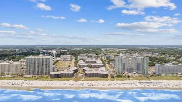 Zona costera con un hotel y varios edificios, una playa y cielo despejado.