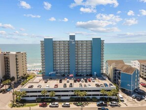 A multi-story hotel with a parking lot in front, located near a beach. - Ocean view Retreat 1BR Condo (Murrells Inlet)