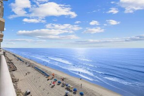 A beach with umbrellas and people, a clear sky, and the ocean. - Ocean view Retreat 1BR Condo (Murrells Inlet)