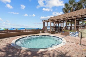 Ein Whirlpool mit Meerblick, eine Holzpergola und ein Schild, das darauf hinweist, dass keine Badeaufsicht gewährleistet ist.