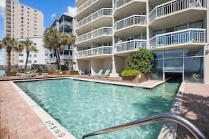 A swimming pool with a 3 FT 5 IN depth marker, surrounded by a brick deck and lounge chairs.