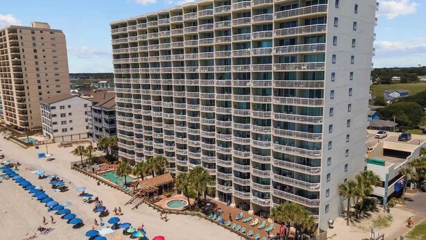 A multi-story hotel with balconies, a pool area, and beachside amenities. - The Tide Calls 1BR Ocean Front (Murrells Inlet)