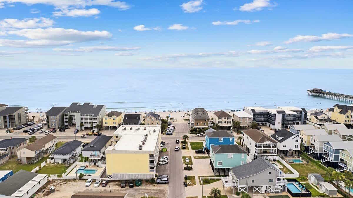 A coastal residential area with multi-story buildings, a beach, and a pier.