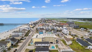Een kustplaats met hotels aan het strand, een pier en een lange weg naar het strand.