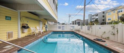 Une piscine dont la profondeur maximale est indiquée à 3 pieds, un espace abrité avec des chaises et une clôture blanche.