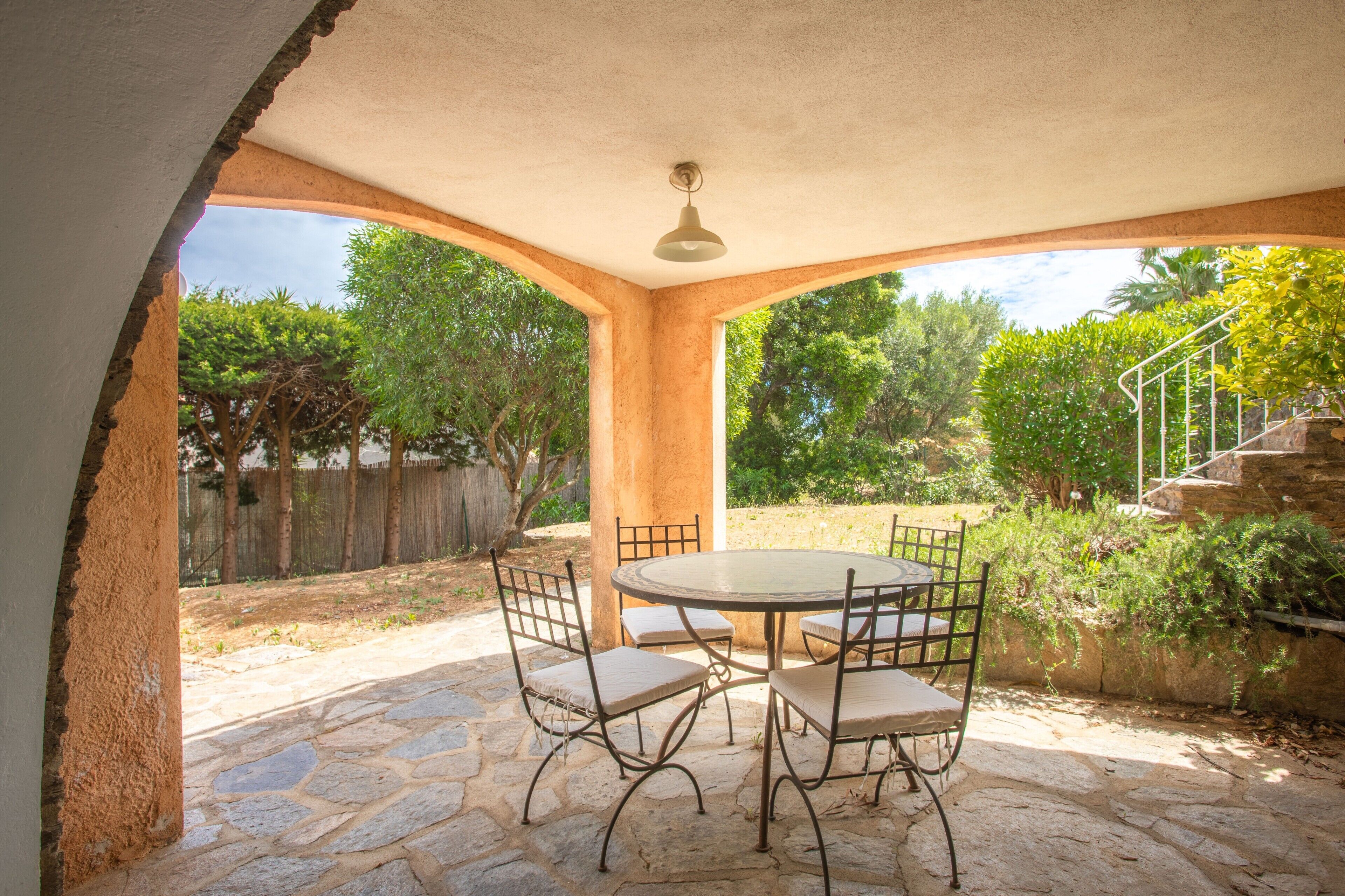A covered patio with a stone floor, a round table, and four chairs.