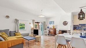 A living room with a sofa, a coffee table, and a dining area with chairs and a table. - La Maison de Valérie: Charming Provençal House Near the Beach for 6 Guests (La Croix-Valmer)