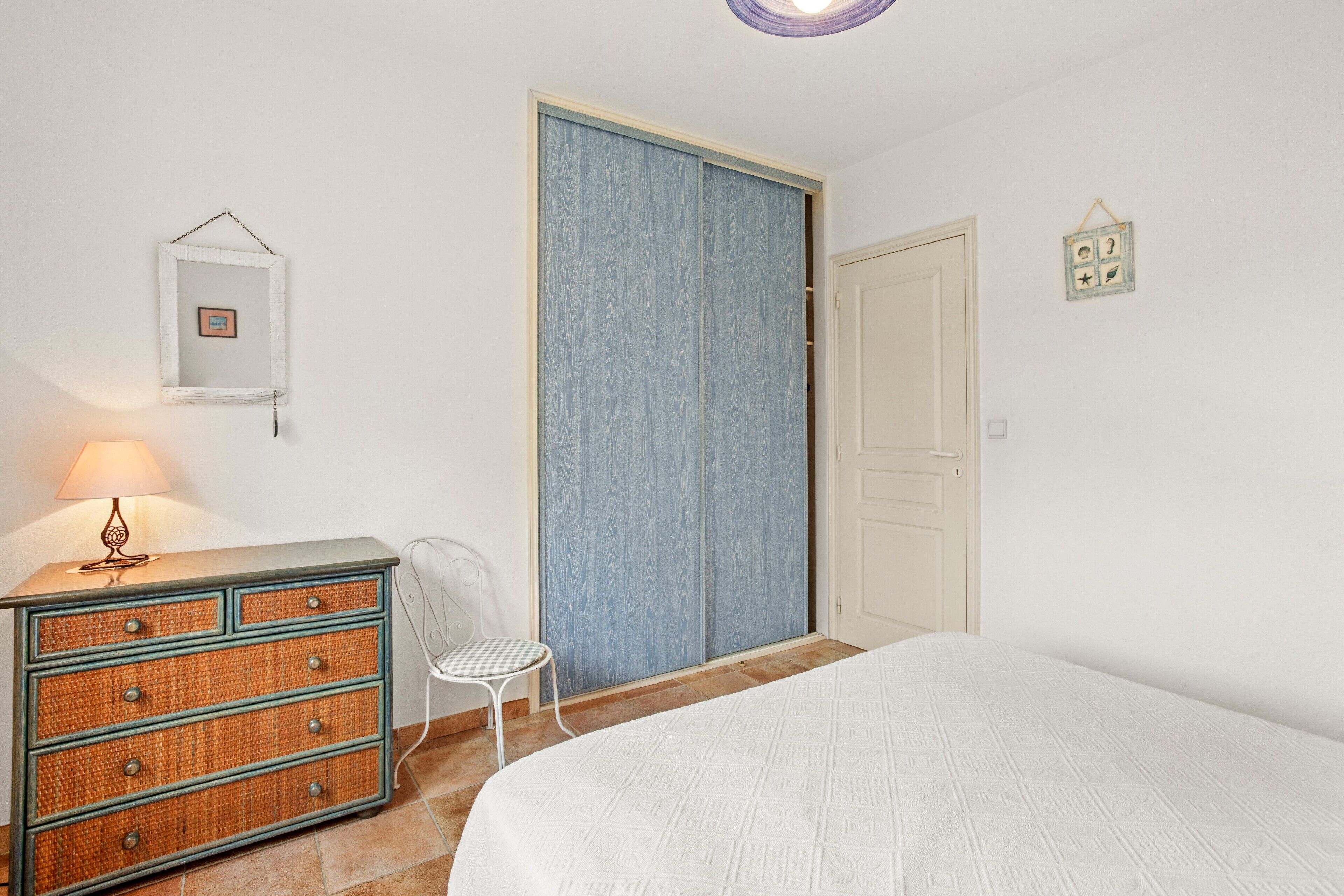A bedroom with a bed, dresser, chair, and a wardrobe.