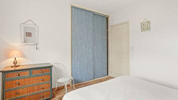 A bedroom with a bed, dresser, chair, and a wardrobe.