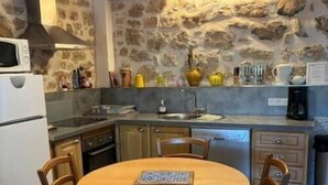 A rustic kitchen with stone walls, wooden furniture, and basic amenities. - Nine - PEYRIAC DE MER (PEYRIAC DE MER)