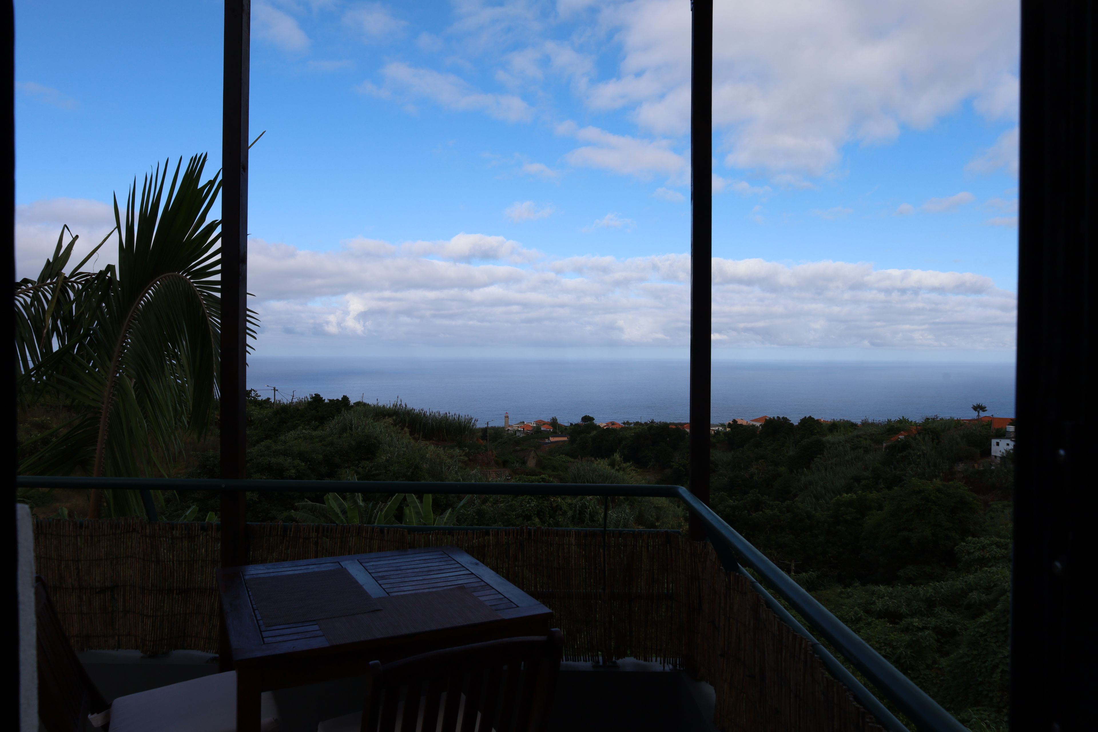 A balcony with a view of the sea and a distant town.