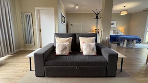 A living room with a sofa, a coat rack, and a bed in the background. - Villa Alta Vista (Sao Jorge)