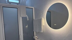 A bathroom with a round mirror, a sink, and a toilet. - Villa Alta Vista (Sao Jorge)