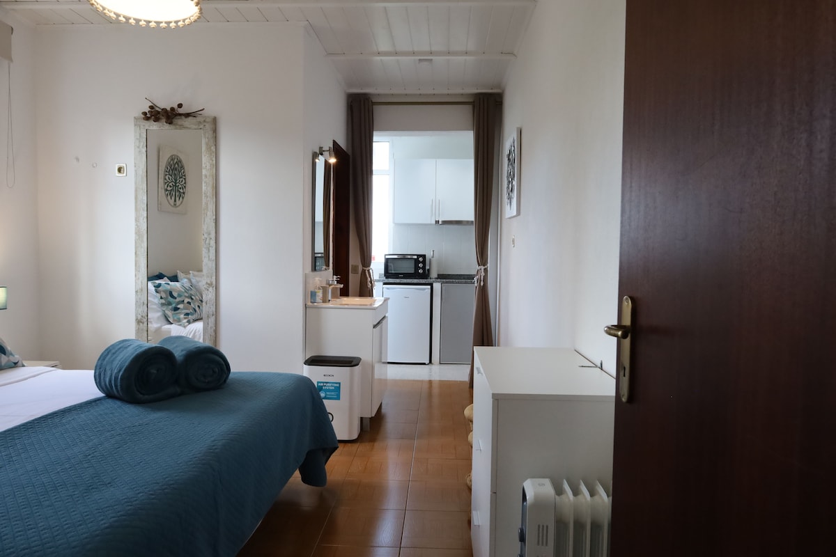 A bedroom with a bed, a bedside table, a dresser, and a window.