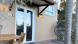 A wooden deck with a table and chairs, a glass door entrance, and a small outdoor seating area. - Villa Alta Vista (Sao Jorge)