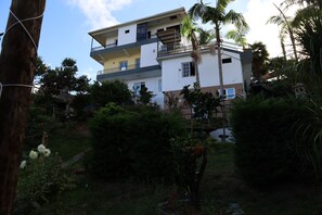 Un edificio residencial de varios pisos con balcones, rodeado de exuberante vegetación y árboles.