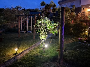 A garden with a swing set, a small tree, and a pathway. - Villa Alta Vista (Sao Jorge)
