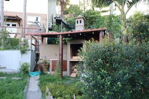 A residential property with a small outdoor kitchen, a wooden pergola, and a garden area with various plants. - Villa Alta Vista (Sao Jorge)