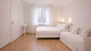 A bedroom with a bed, bedside tables, a window with curtains, and a radiator. - Morning in Prague – Cozy Entire Home for 15, 1 min to Tram, 4 Rooms & 2 Kitchens (Praha2)