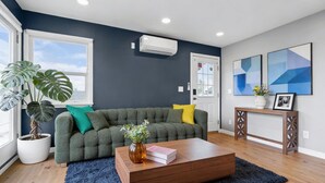 Ein Wohnzimmer mit einer Couch, einem Couchtisch, einer Topfpflanze und Bildern an der Wand.