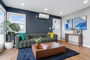 A living room with a sofa, a coffee table, a potted plant, and artwork on the wall. - Terrace Living Near SoFi (Hawthorne)