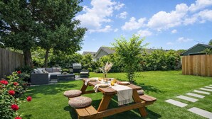 Ein Garten mit Picknicktisch, Gartenmöbeln und einem gepflegten Rasen.