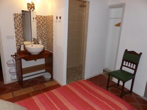 Un baño con lavamanos, espejo, ducha y una silla.