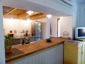 Una cocina con encimera de madera, un refrigerador, un microondas y un lavamanos.